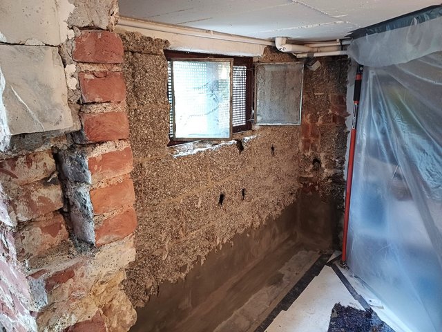 Freigelegte Kellerwand mit aufgetragener grauer Masse am Sockel