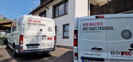 Zwei ISOTEC Fahrzeuge stehen vor einem Wohnhaus.