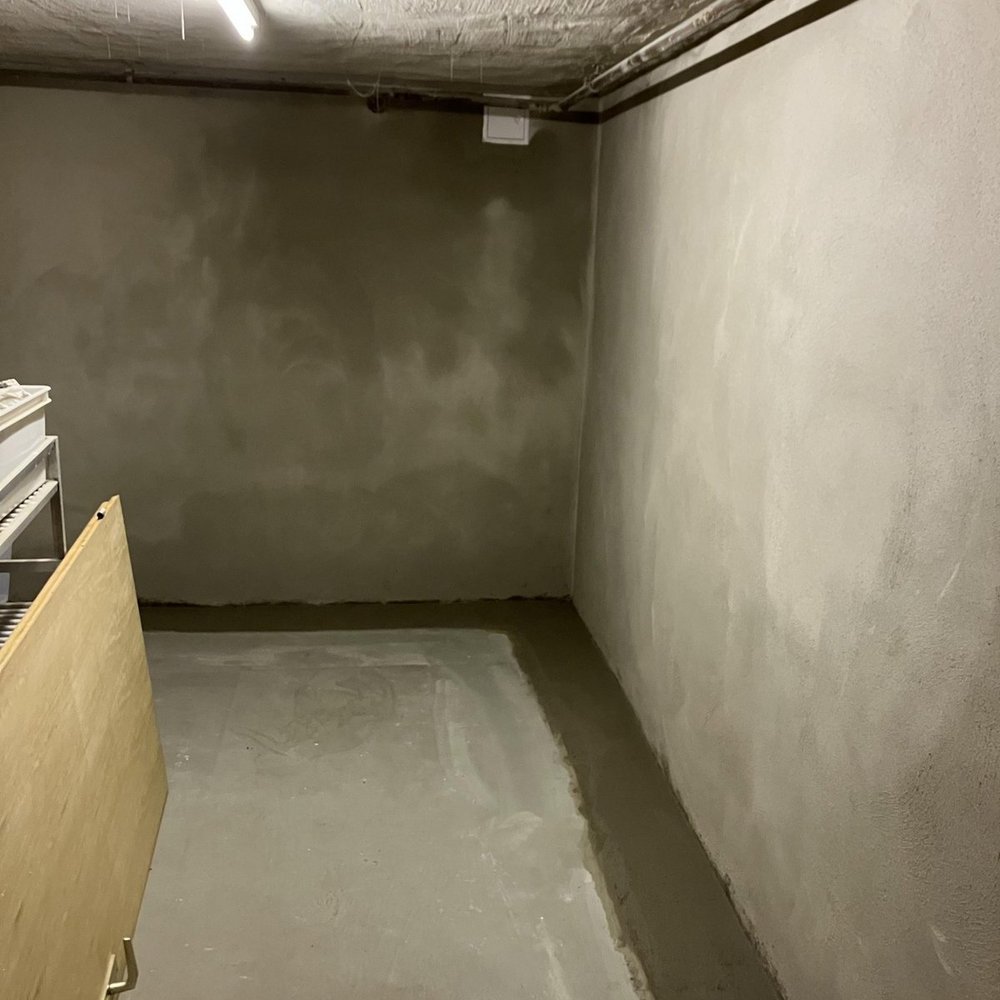 Sanierter Kellerraum mit grauer Bodenbeschichtung und verputzten Wänden