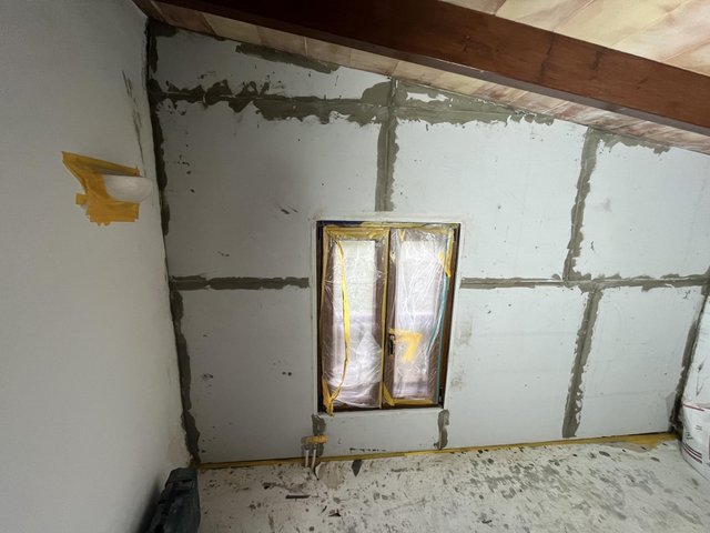 Abgeklebtes Fenster in Raum mit hellen Platten und grauen Fugenstreifen