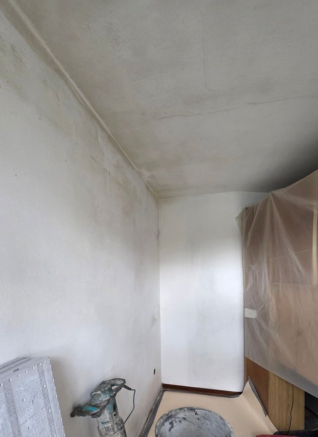Verfärbte Zimmerwand und Decke mit Rissen, Renovierungswerkzeuge im Raum