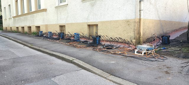 Kabel und Geräte entlang der Gebäudewand auf Gehweg aufgebaut