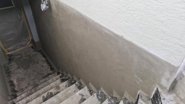 Graue Masse auf Wand im Treppenabgang, Blick von oben auf Stufen
