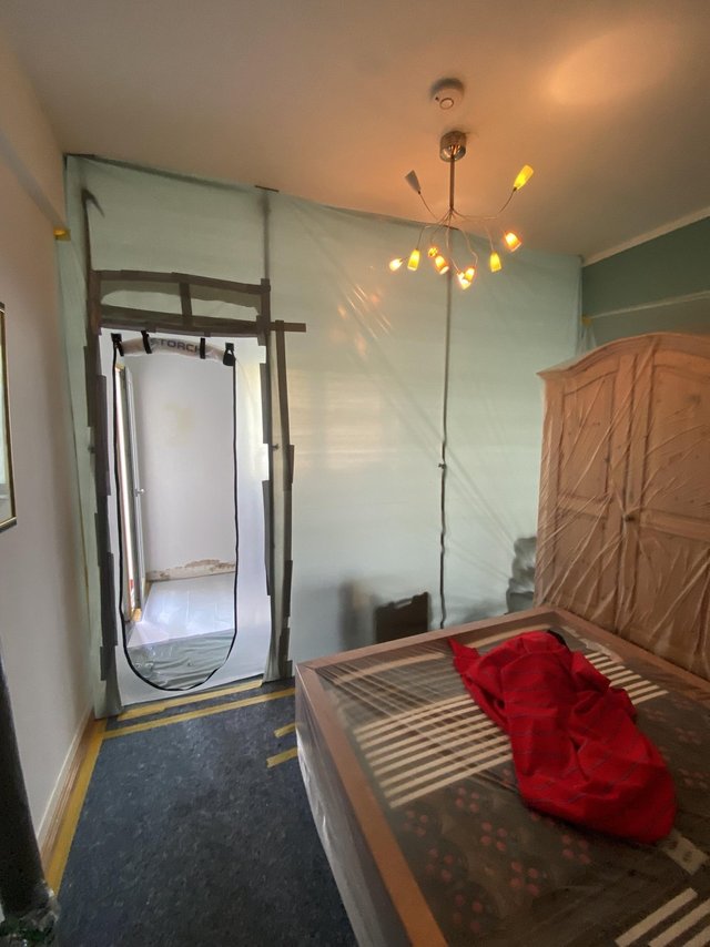 Schlafzimmer mit Staubschutzfolie und abgeklebtem Zugang während Sanierungsarbeiten