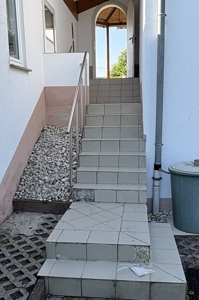 Geflieste Außentreppe mit Edelstahlgeländer an Hauseingang