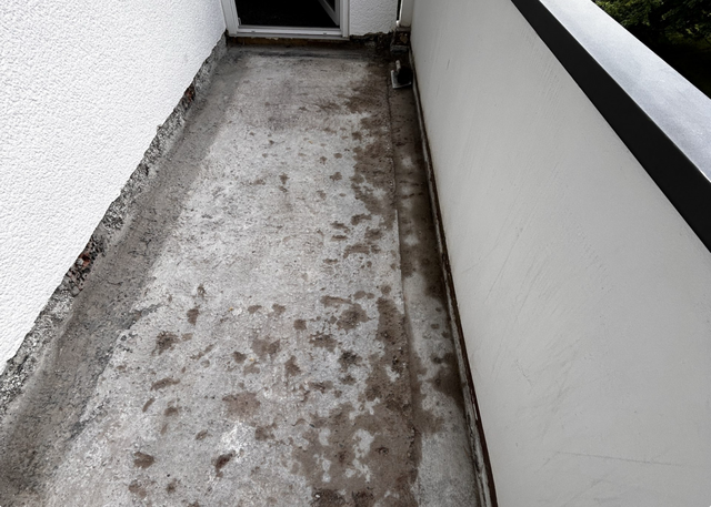Verschmutzter Betonboden auf schmalem Balkon, Draufsicht