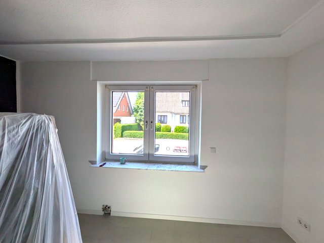 Leerer Raum mit Fenster, abgedeckten Möbeln und Werkzeugen auf Fensterbank