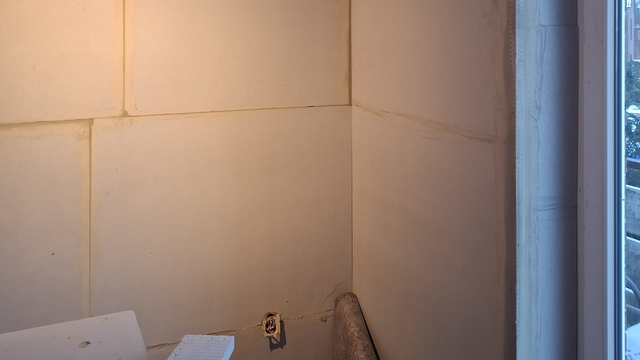 Helle Plattenwand mit sichtbaren Fugen neben einem Fenster