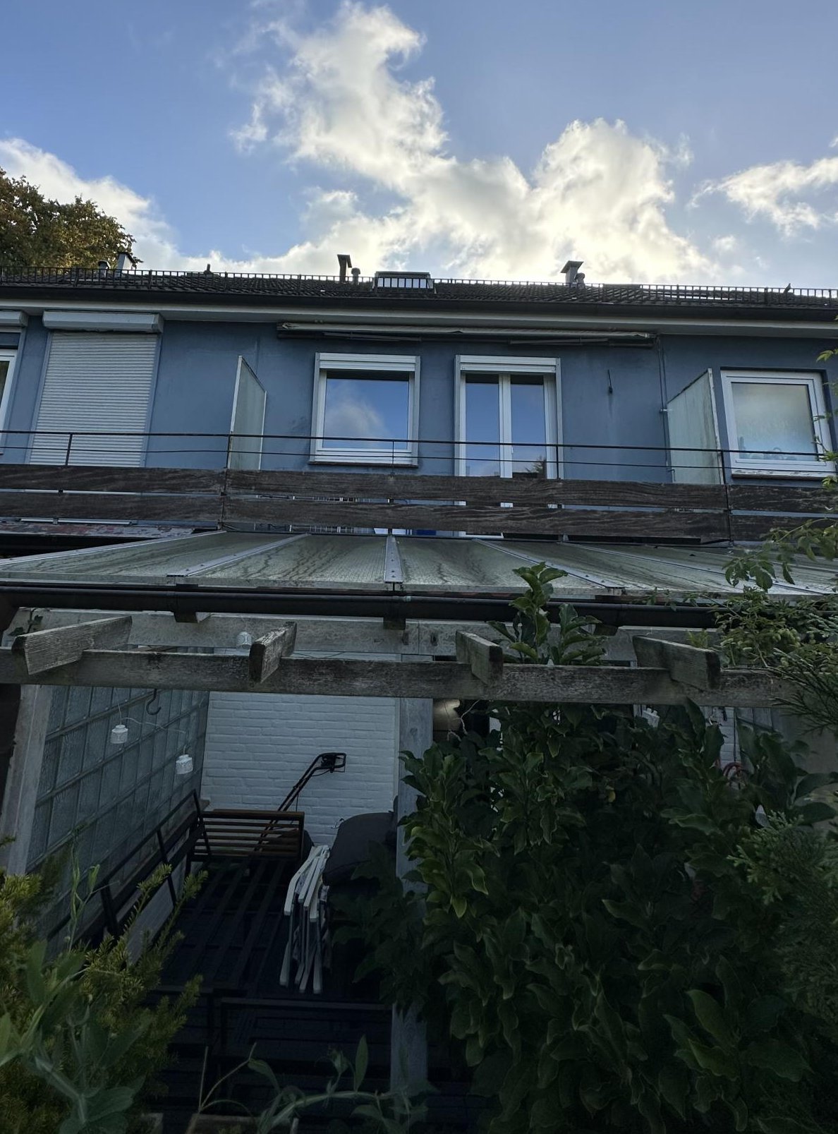Mehrstöckiges Wohnhaus mit Fenstern und Wintergarten, Blick nach oben in den Himmel.