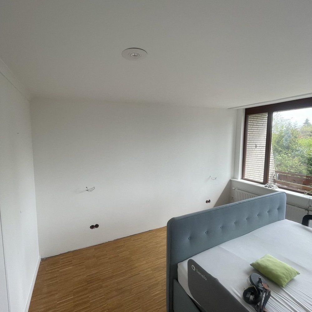 Leeres Zimmer mit weißer Decke, Bett am Fenster und Holzfußboden