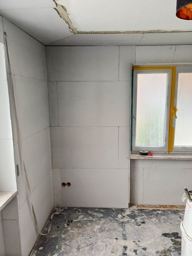 Raum mit hellgrauen Dämmplatten an den Wänden, Fenster mit gelbem Abklebeband
