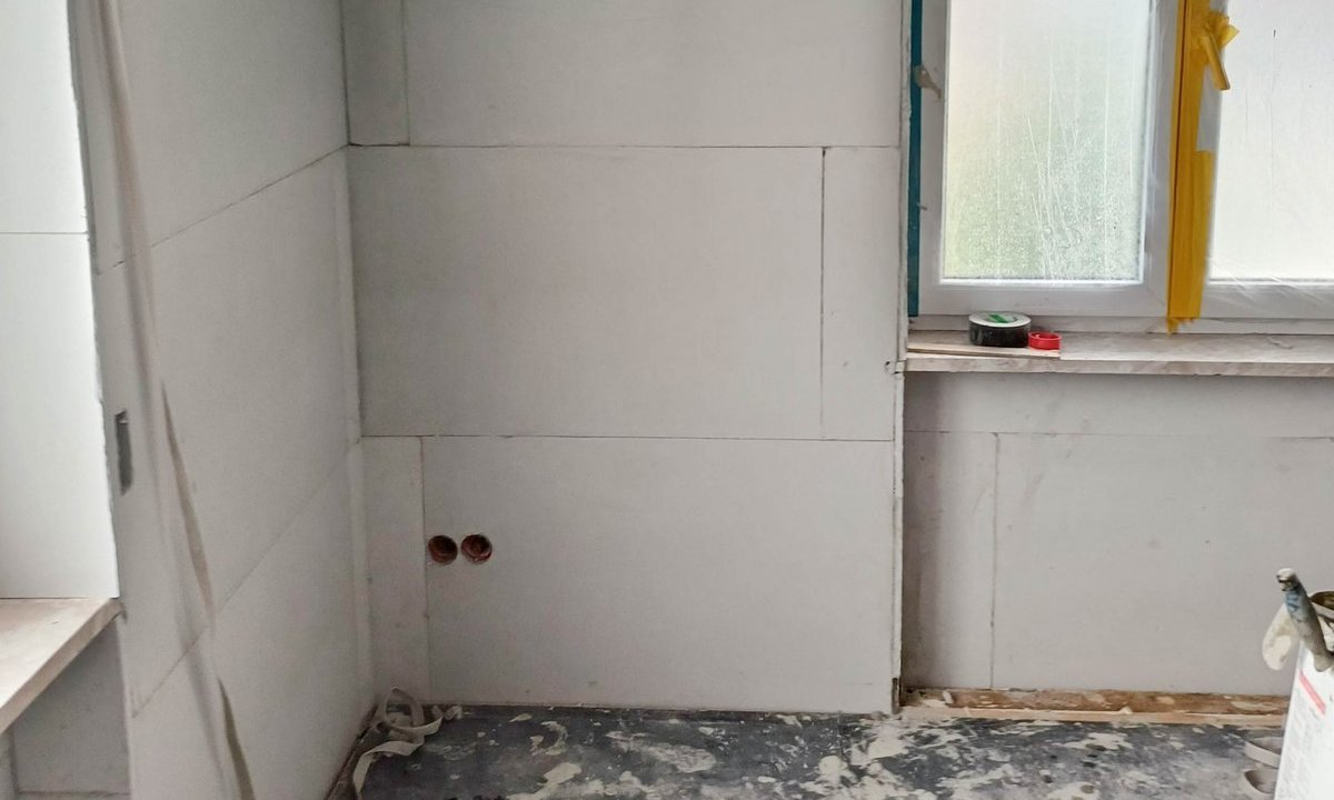 Raum mit hellgrauen Dämmplatten an den Wänden, Fenster mit gelbem Abklebeband