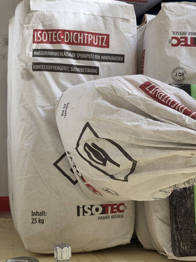 Stapel weißer Säcke mit ISOTEC-Dichtputz, 25-kg-Aufdruck und Warnsymbol