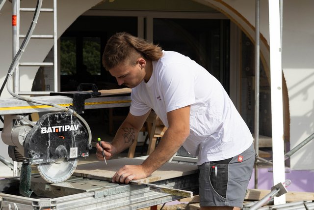 Handwerker markiert beige Fliese mit Stift auf Fliesenschneidemaschine