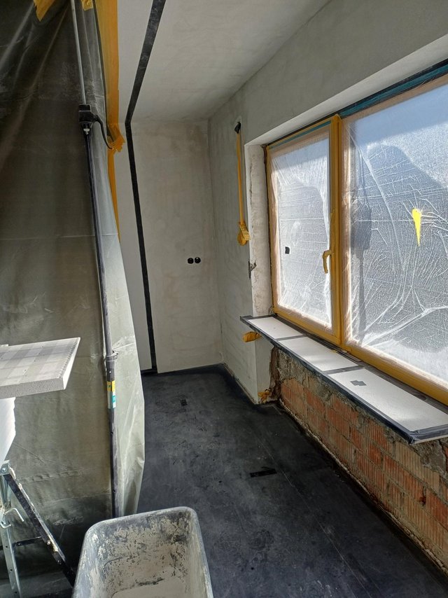 Renovierungsraum mit abgeklebtem Fenster und offener Ziegelwand