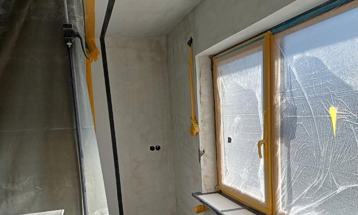 Renovierungsraum mit abgeklebtem Fenster und offener Ziegelwand