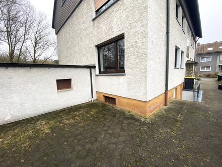 Gebäudeecke mit heller Fassade, Fallrohr und Hofbereich