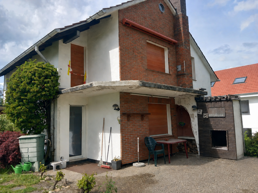 Zweigeschossiges Wohnhaus mit Ziegel- und Putzfassade, Rolllaeden geschlossen, Hofansicht.