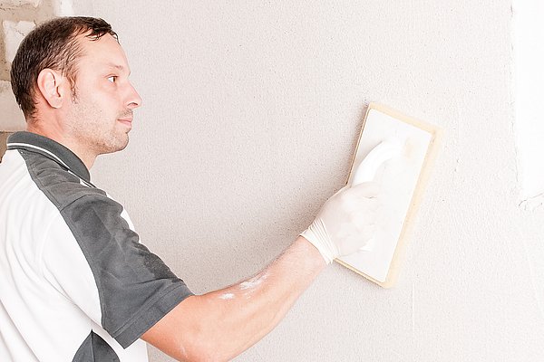 Zur Sanierung feuchter Wände trägt ISOTEC Facharbeiter Sanierputz auf das Mauerwerk auf.