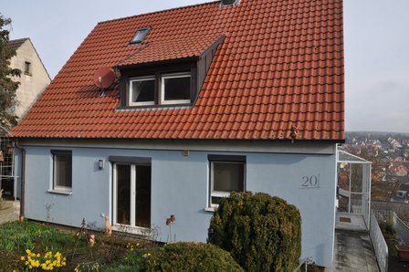 Wohnhaus mit rotem Ziegeldach, Gaube und grauer Fassade, Hausnummer 20
