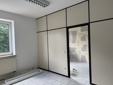 Leerer Raum mit Fliesenboden, Fenster und Türöffnung zu Raum mit gespachtelten Platten