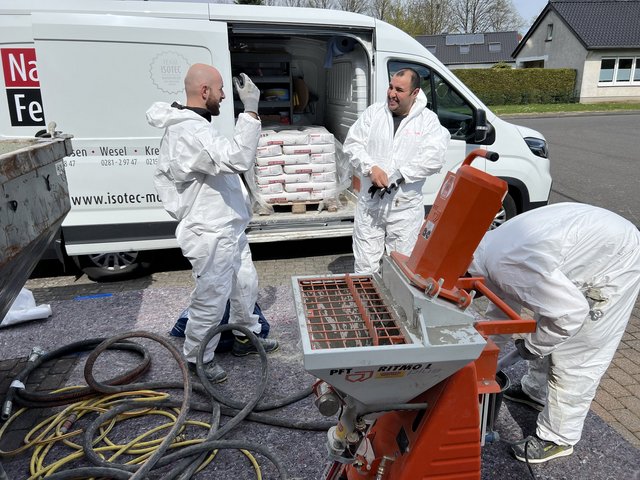 ISOTEC Mitarbeiter bereiten Spritzmaschine und Materialsäcke vor einem Transporter vor
