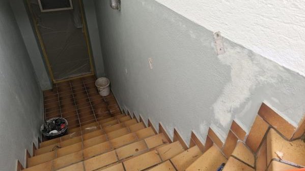 Treppenabgang mit grauer Wand und heller Masse an der unteren Wandfläche.
