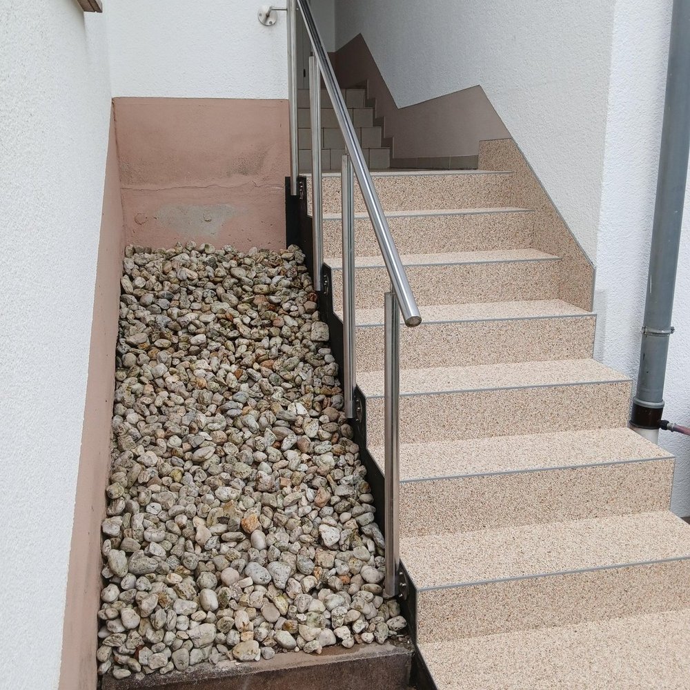 Hauseingang mit Steintreppe, Edelstahlgeländer und Kiesfläche