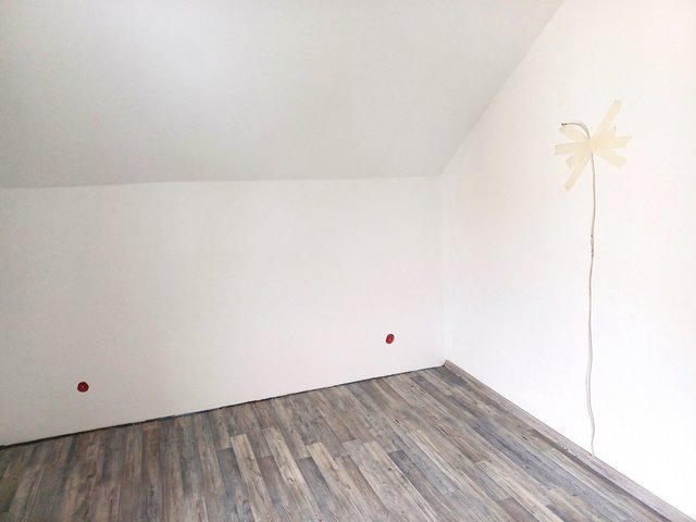 Leeres Zimmer mit weißer Wand, Holzboden und fixiertem Kabel