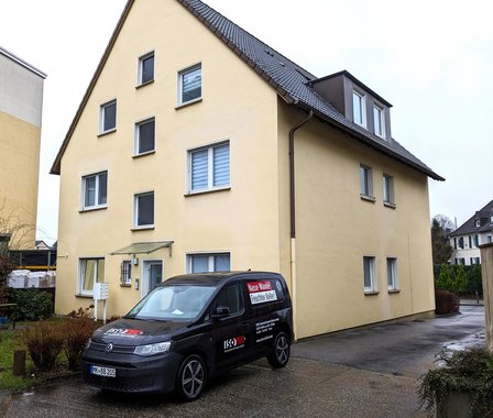 ISOTEC Transporter vor Wohnhaus mit hellgelber Fassade und mehreren Fenstern