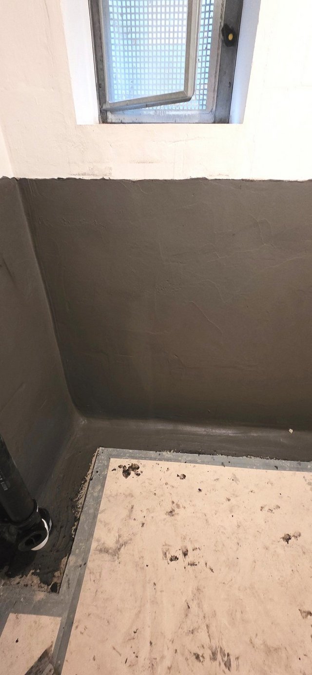 Schwarze Masse auf Wand unter Kellerfenster, Bodenbereich mit Abdeckplatte