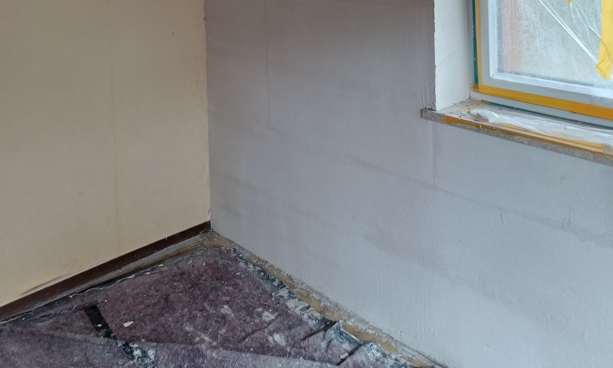 Abgeklebtes Fenster neben Wand mit hellen rechteckigen Platten und Holzdecke