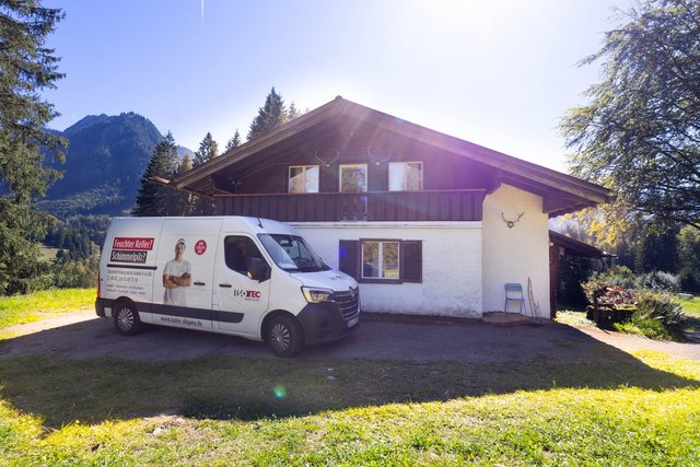 ISOTEC Transporter steht vor Einfamilienhaus in bergiger Landschaft.