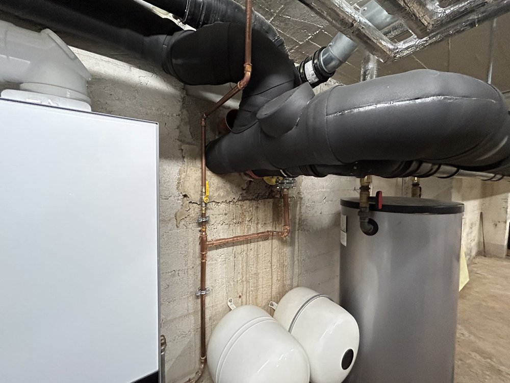 Rissige Kellerwand mit Kupferleitungen und isolierten Rohren