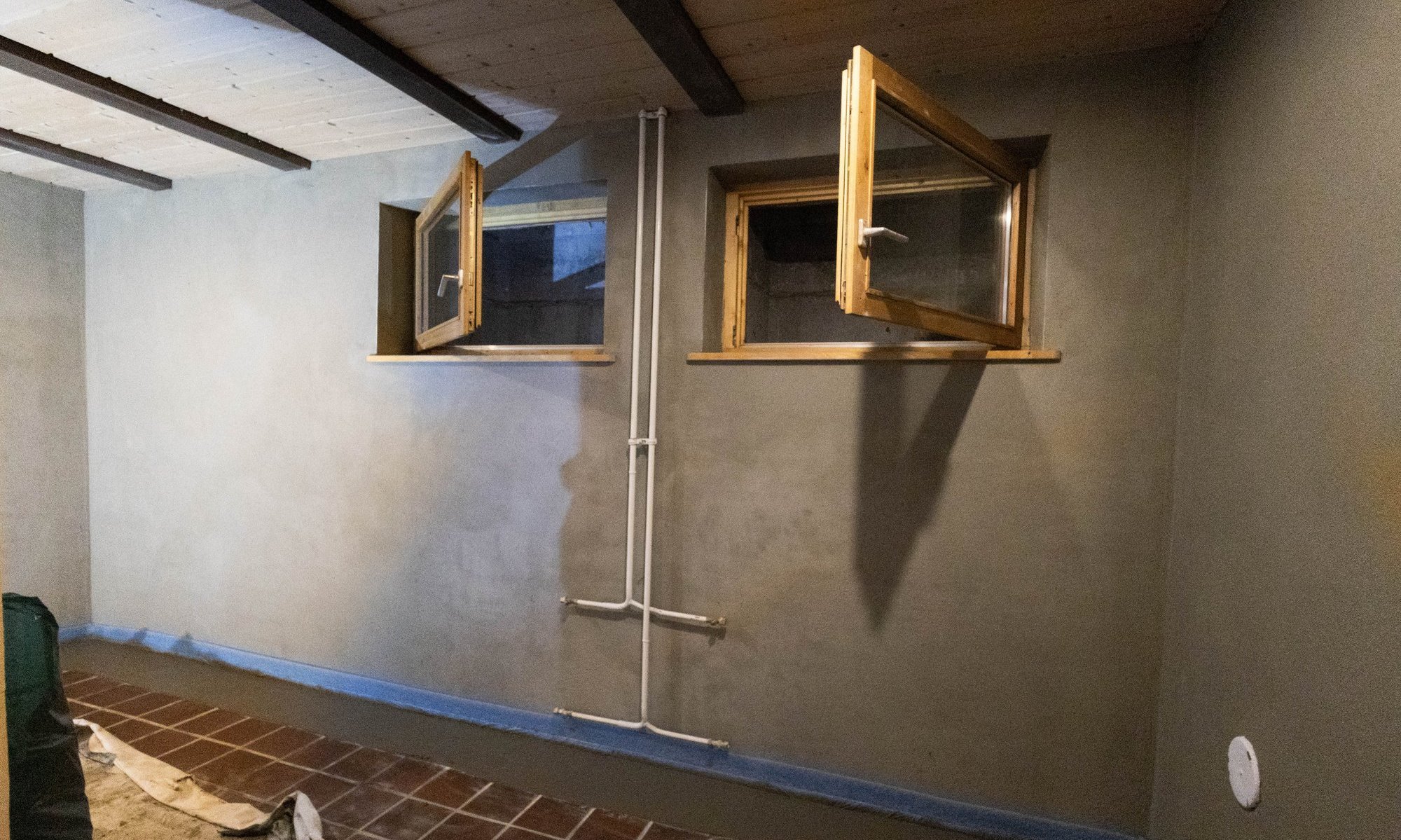 Graue Wandbeschichtung in Kellerraum mit zwei geöffneten Fenstern