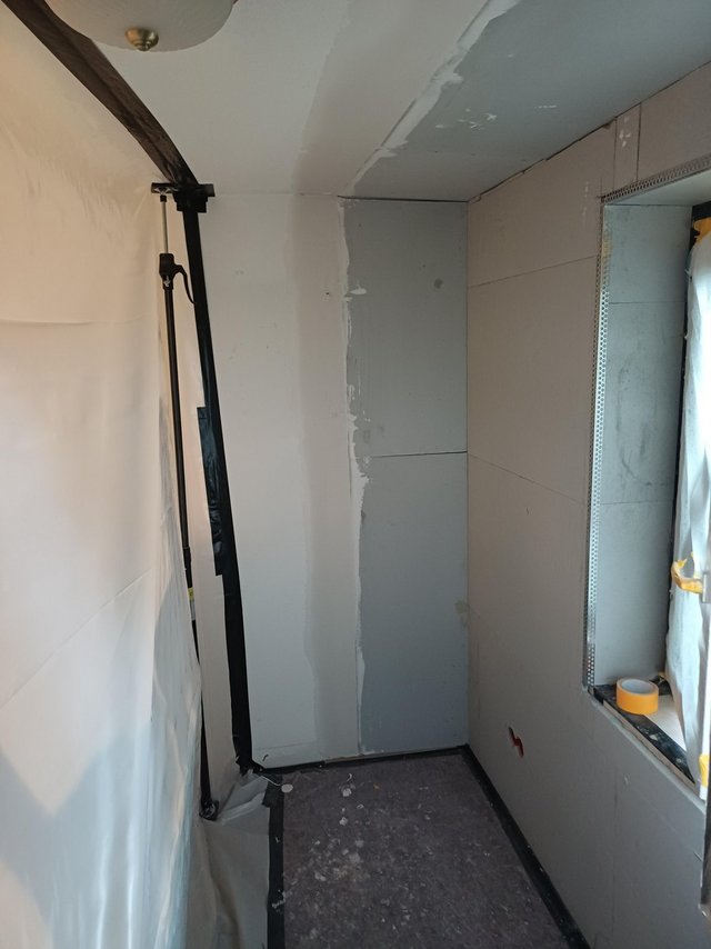 Schmaler Raum mit hellen Platten, Folie und verspachtelter Decke