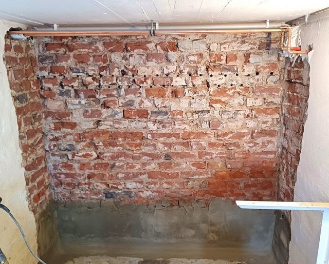 Freigelegte Ziegelwand mit unterer grauer Mörtelschicht