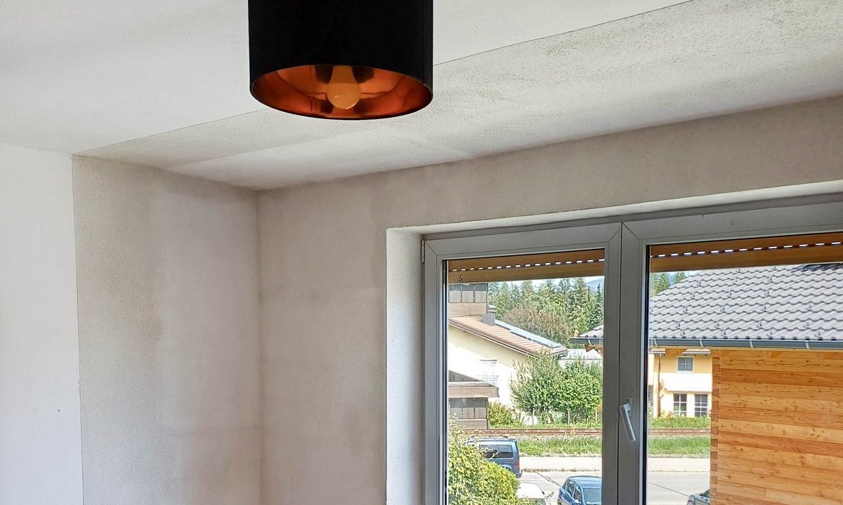 Leerer Raum mit heller Wand, Holzboden und Fenster mit Blick auf eine Straße