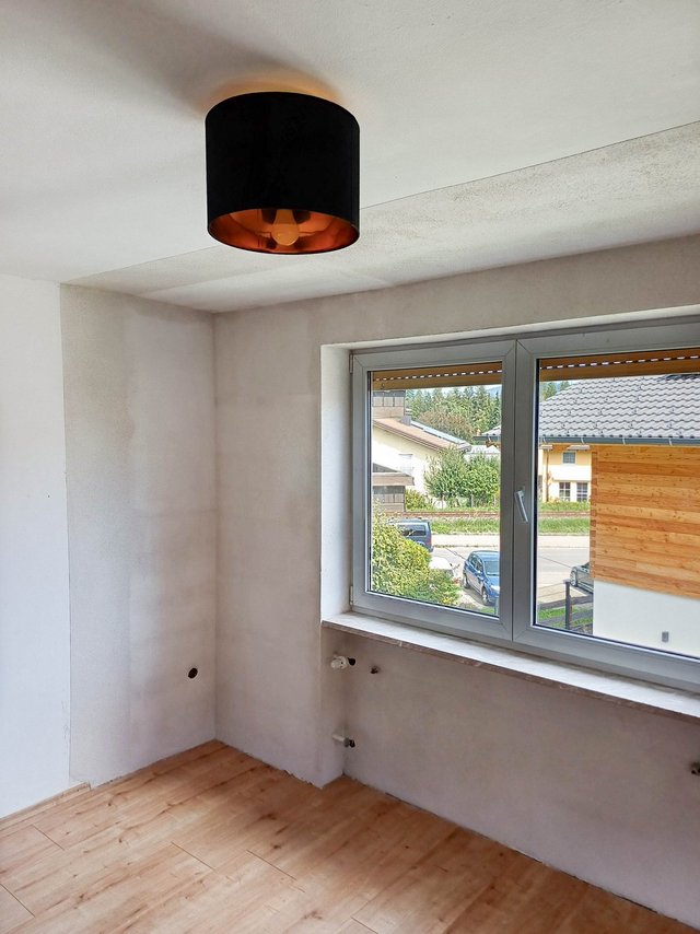Leerer Raum mit heller Wand, Holzboden und Fenster mit Blick auf eine Straße