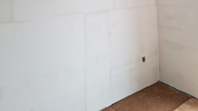 Helle Wand mit sichtbaren Plattenkanten und offenem Wandausschnitt