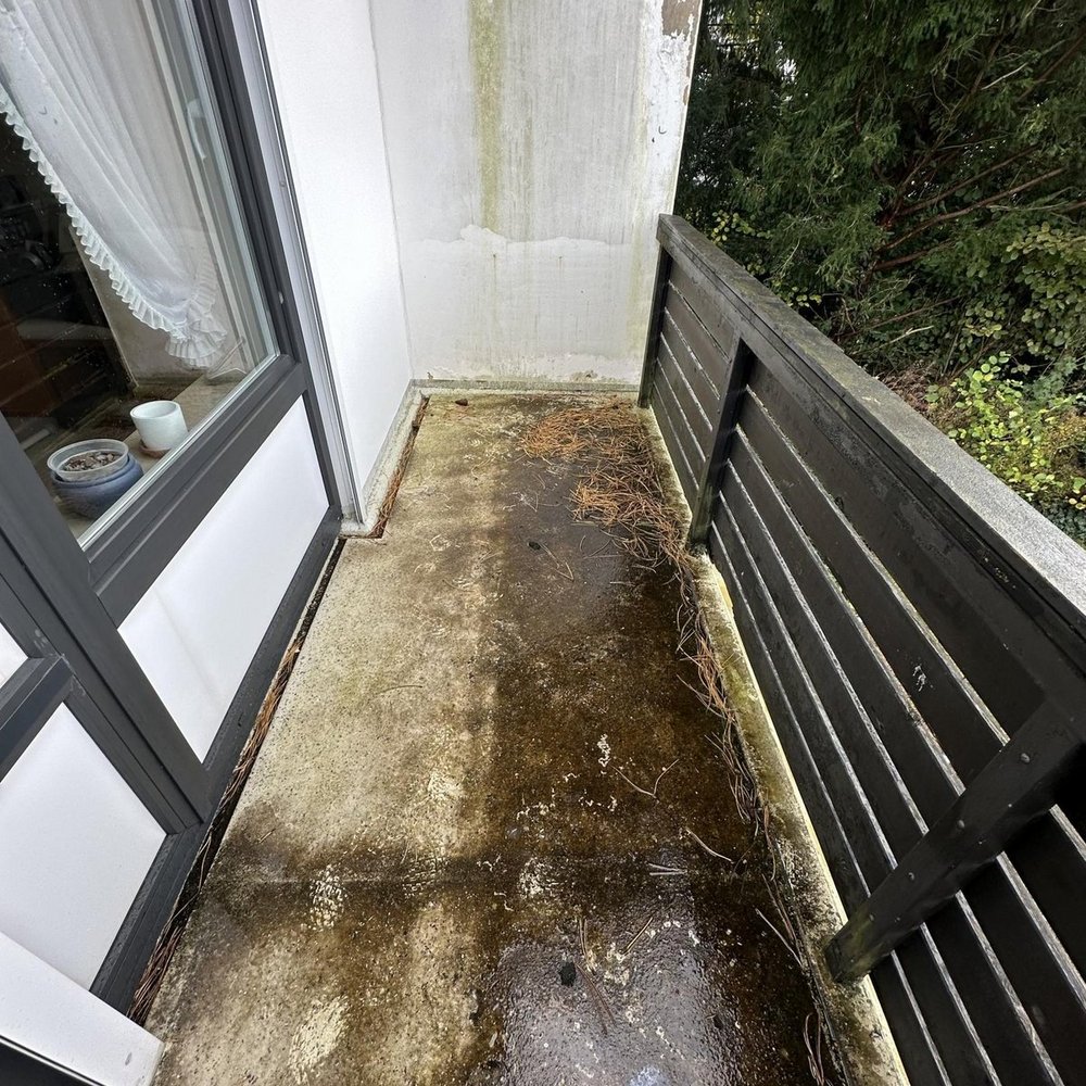 Verschmutzter Balkon mit nassem Boden, Algenbelag und verfärbter Wand