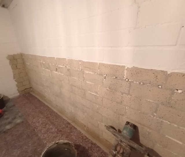 Freigelegte Kellerwand mit heller Steinreihe und Werkzeugen am Boden