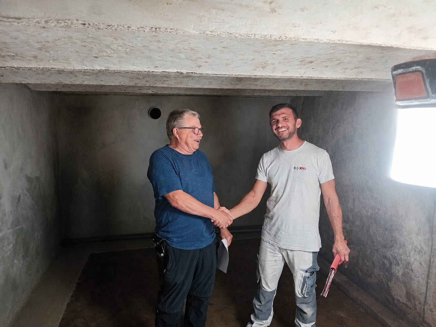 ISOTEC Mitarbeiter schuttelt Kunde im Kellerraum die Hand.