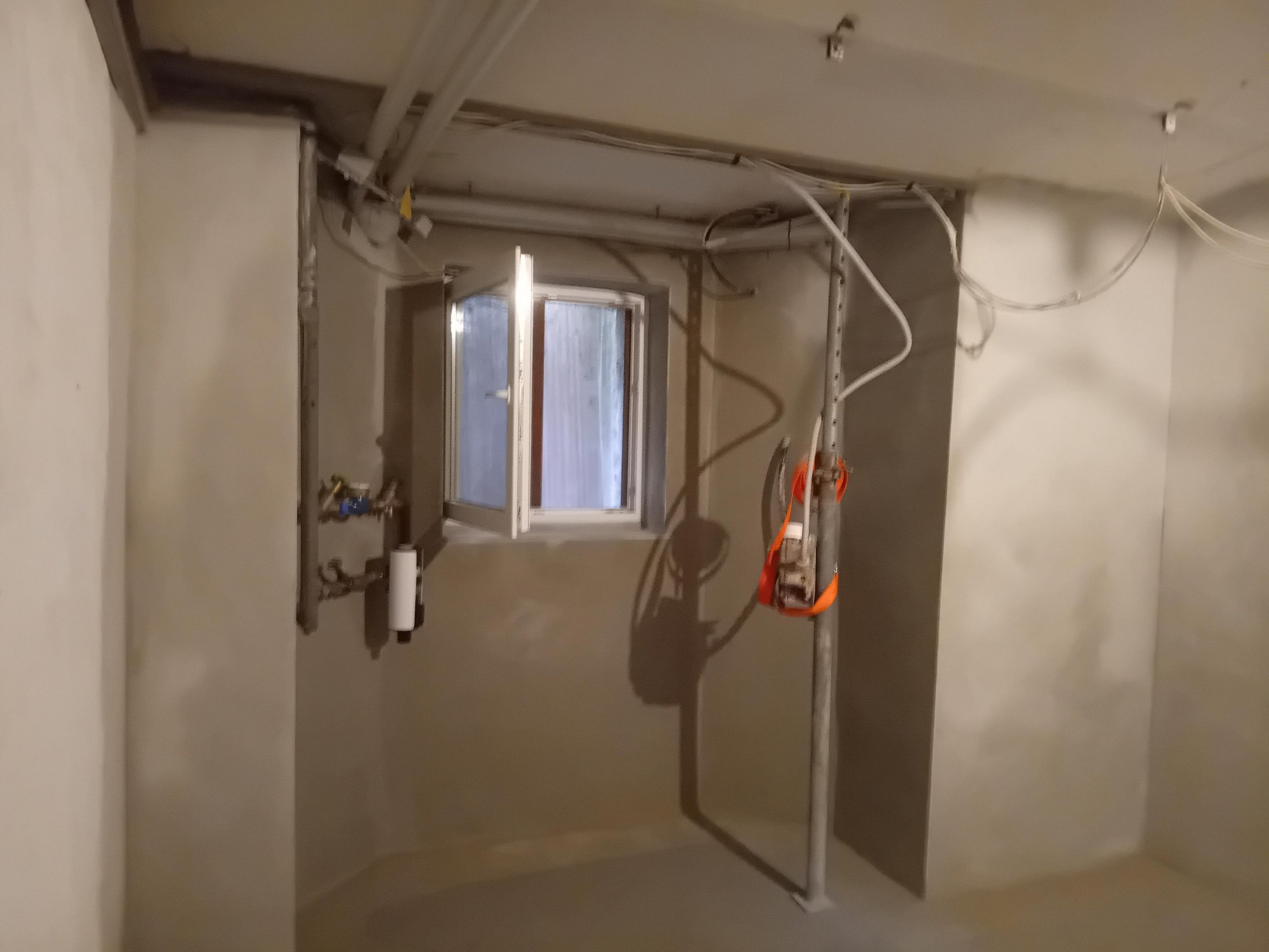 Kellerraum mit offenem Fenster, Leitungen und freihängenden Kabeln an der Decke