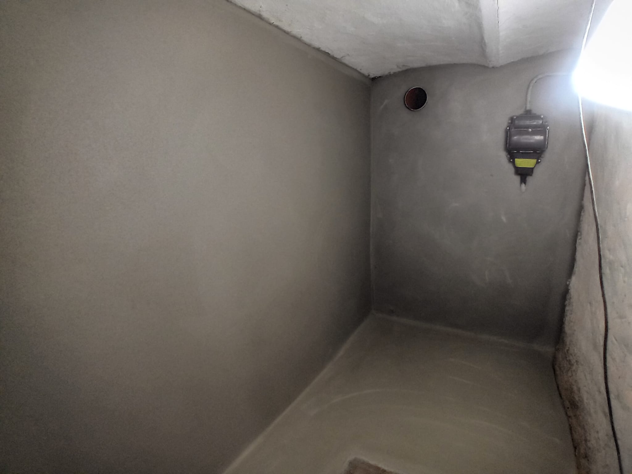 Graue beschichtete Raumdecke und Wand mit rundem Rohrdurchlass und montiertem Gerät