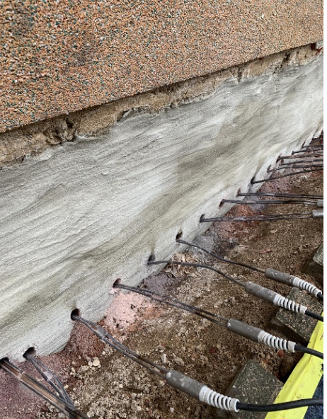 In Kellerwand eingebrachte Metallstäbe unter grauer Masse, Nahaufnahme