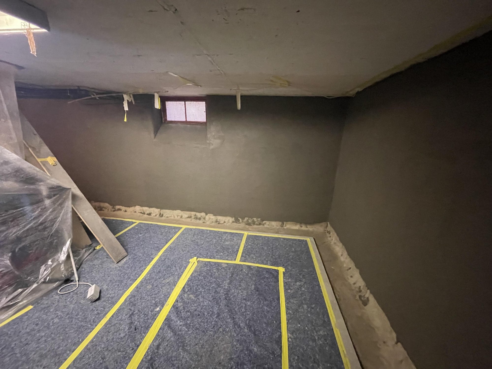 Beschichtete Kellerwände und abgeklebter Boden im Raum