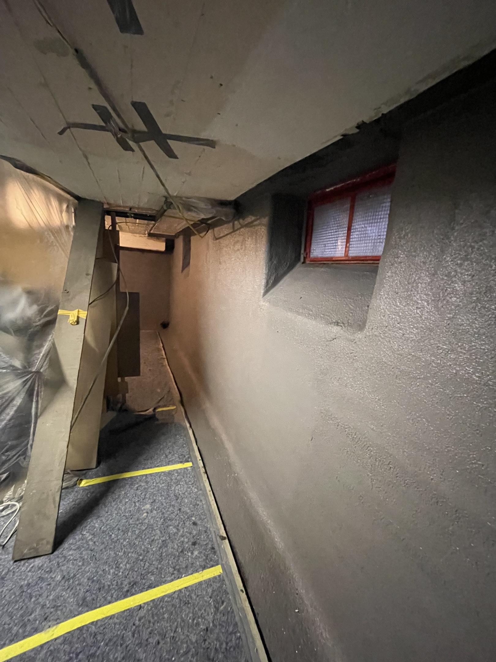 Glatte graue Kellerwand in engem Gang