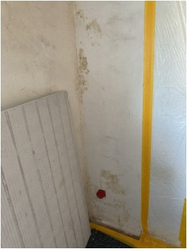 Fleckige Wand mit Feuchtigkeitsspuren, helle Platte lehnt daneben