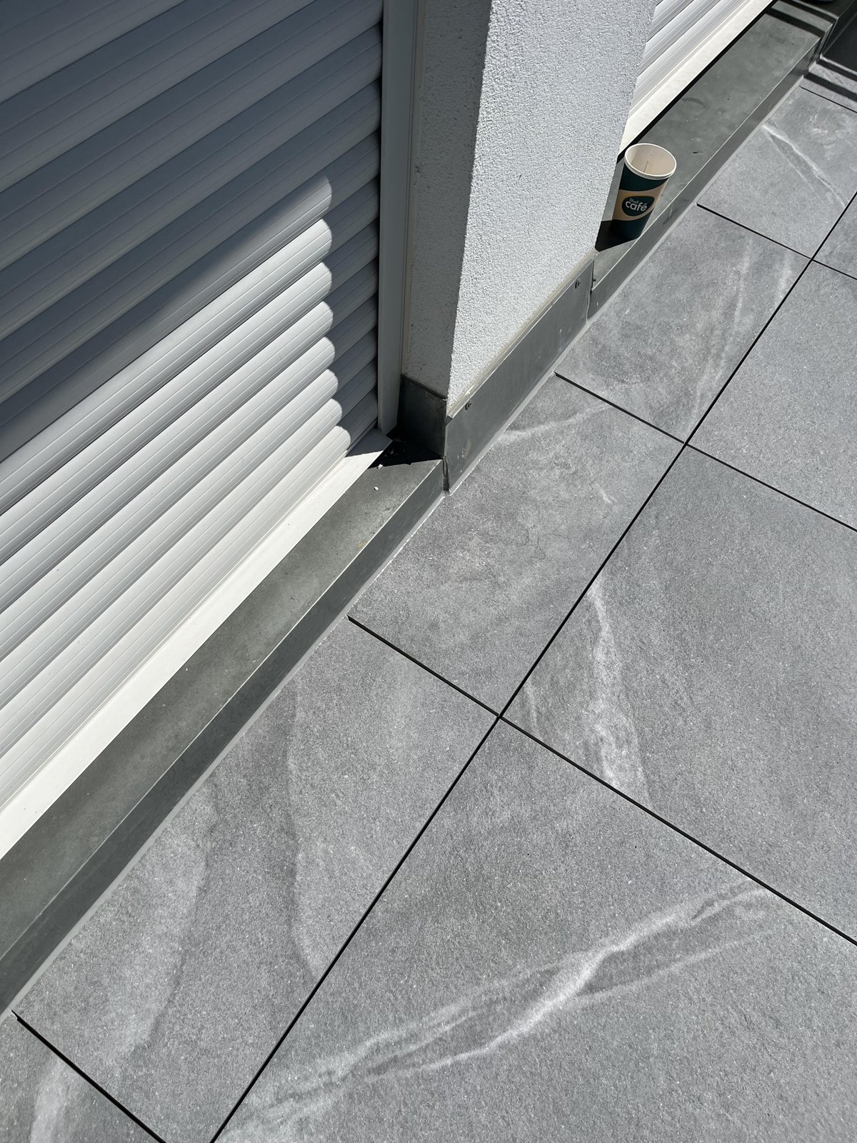 Graue Bodenfliesen an Balkon mit Rollladen und Metallanschluss